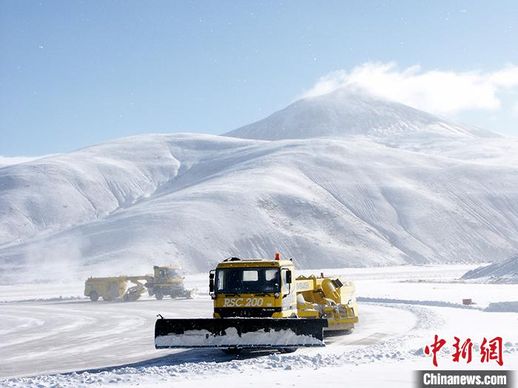 机场工作人员驾驶扫雪车清理被大雪覆盖的机场跑道